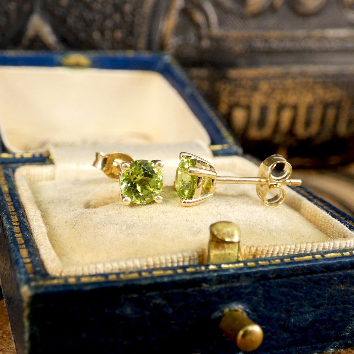 Four-claw peridot stud earrings crafted in 9ct yellow gold, featuring vibrant round-cut green gemstones with a classic and elegant design.