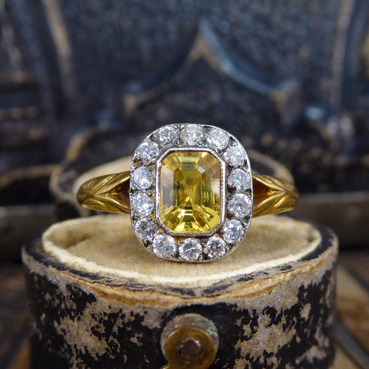 Georgian style cluster ring, a ring that has taken inspiration for an antique era. Ring sat on an antique box showing a Central Yellow Sapphire surrounding by a cluster of 14 Diamonds.