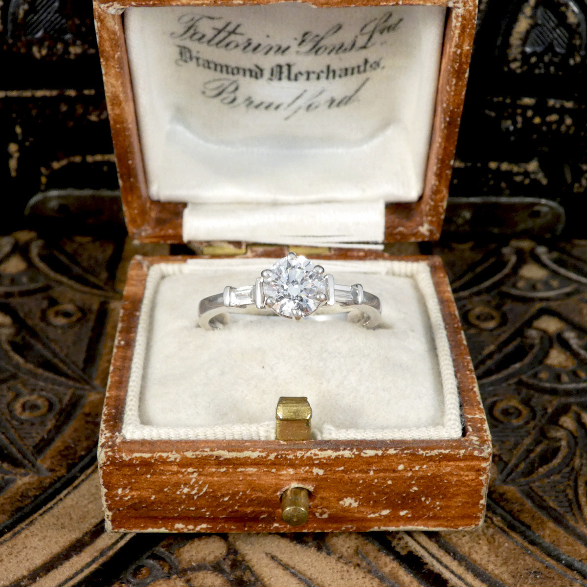 A classic brilliant cut diamond solitaire with baguette cut diamond shoulders in 18ct white gold. GIA certed diamond in a six claw setting, the perfect engagement ring. Shown in vintage ring box.