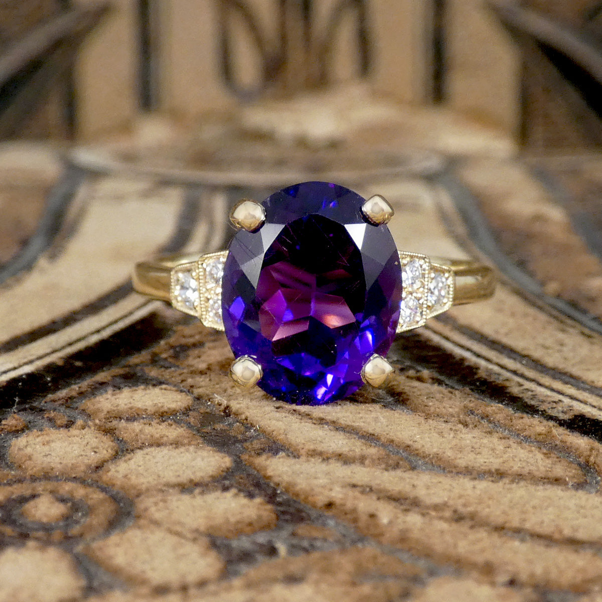 Bright and vibrant amethyst ring in a four claw setting with diamond set shoulders in 9ct yellow gold.