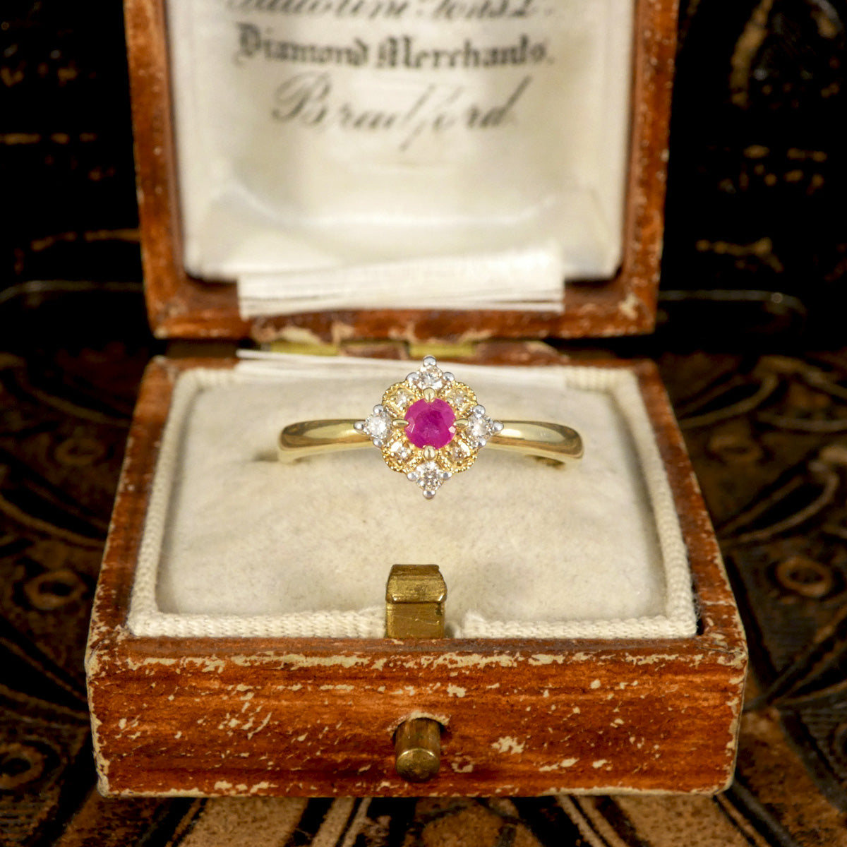 The perfect gift. Modern ring with vintage aesthetic shown in vintage box. Ruby and Diamond Cross Section Illusion Set Ring in Yellow and White Gold showing a bright pink hue in the ruby and a gold cluster ring with a difference.