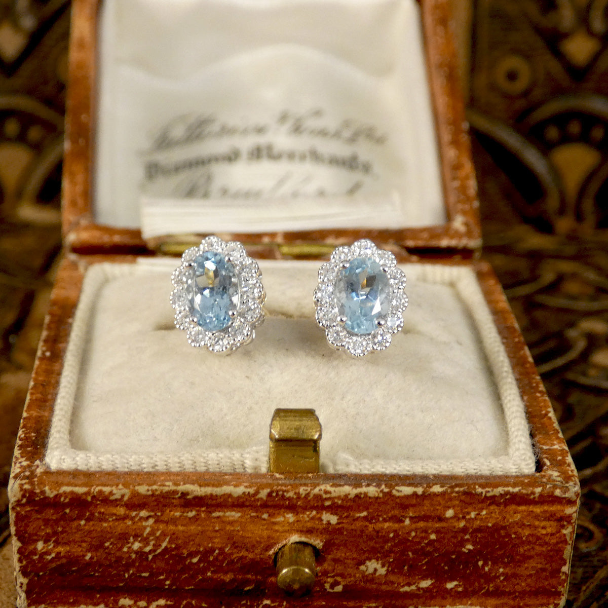 Aquamarine and Diamond cluster earring sin 18ct white and yellow gold. Light to medium oval cut aquamarines in a four claw setting with smaller brilliant cut diamonds creating lots of sparkle. Shown in vintage box to reflect style of earrings.