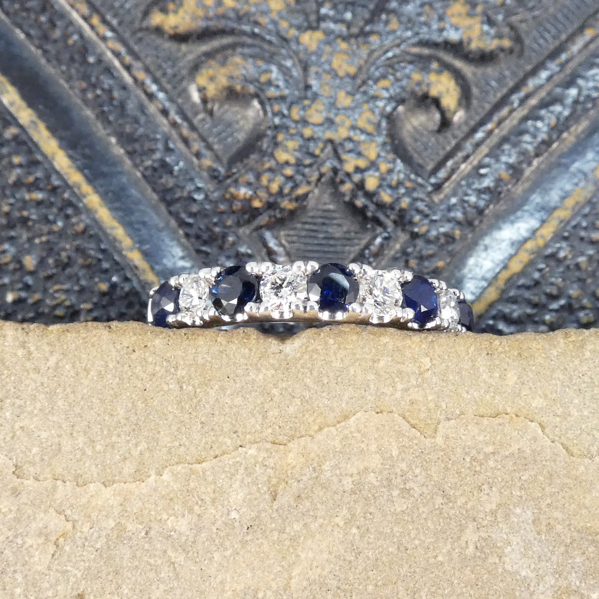 Alternating blue Sapphire and Diamond half eternity ring in white gold to complement the stones. Showing the claw settings on the ring and clear bright stones.