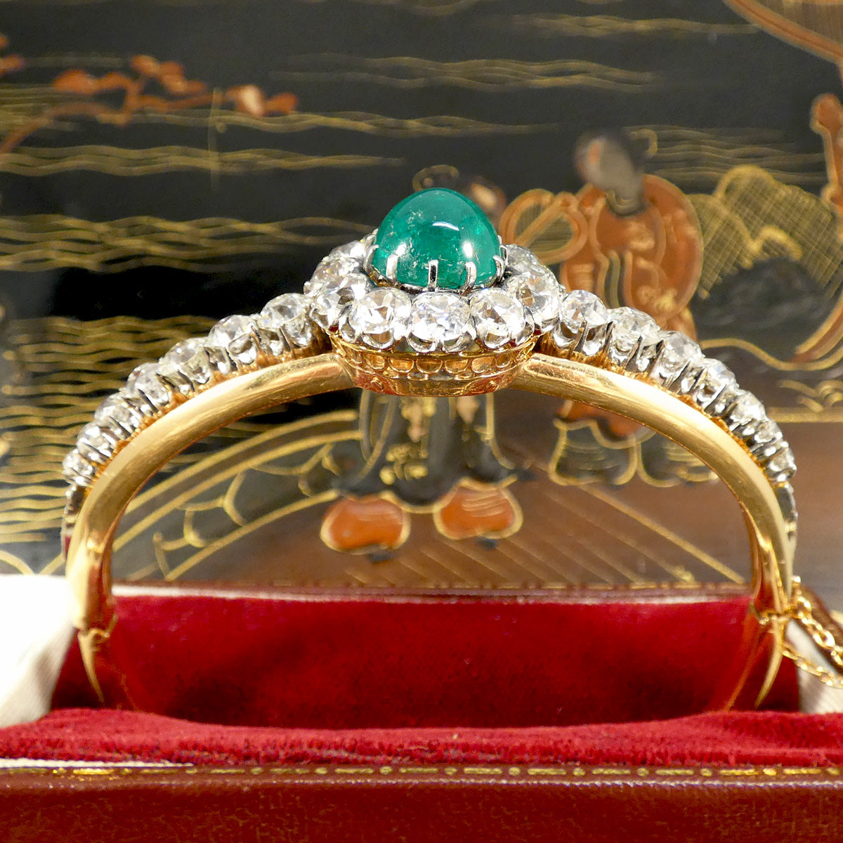 Close-up of a late Victorian cabochon emerald and diamond bangle, showcasing an approximate 5.30ct vibrant green emerald surrounded by sparkling diamonds, emphasising its luxurious and timeless design.