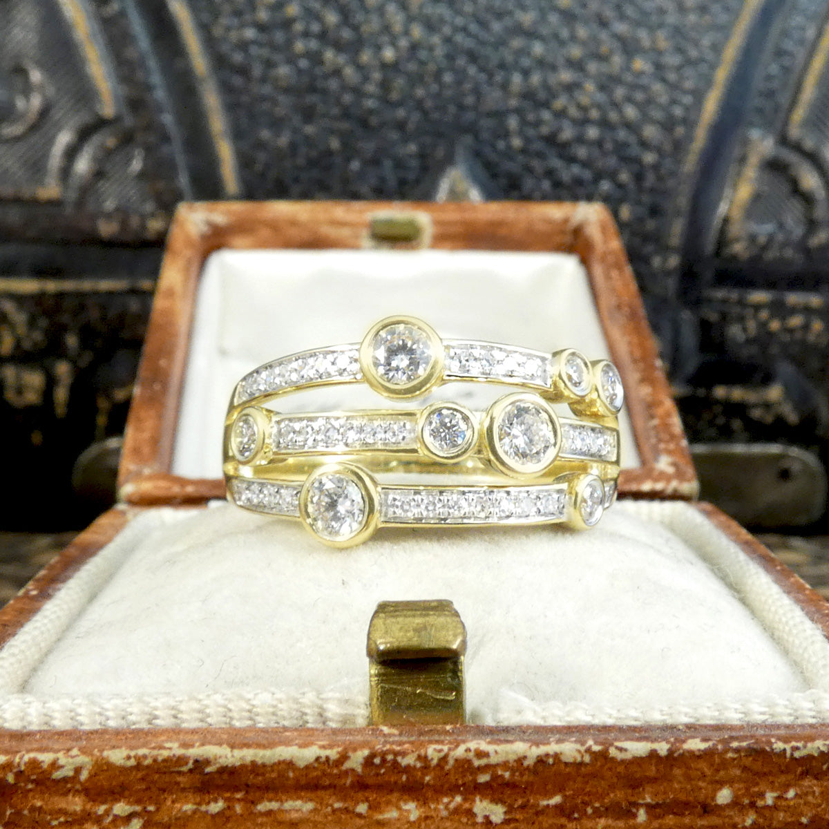 A modern bubble style diamond set ring. With larger and smaller Diamonds bezel set into three bands across a the head of the ring. A great gift idea and statement ring. All fully made in 9ct Yellow Gold with a warm beautiful aesthetic. Shown in vintage box.