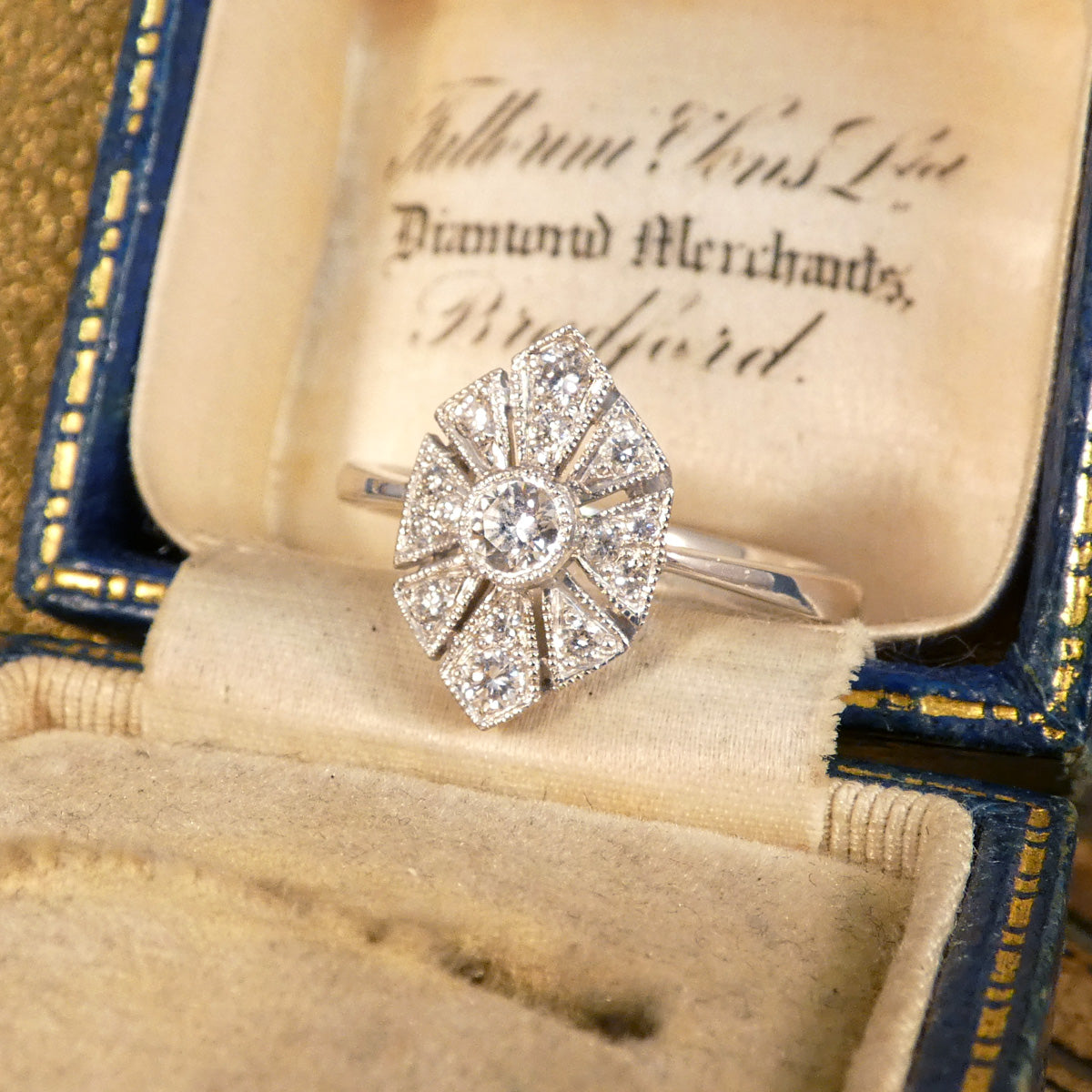 Art Deco-inspired replica ring crafted with exquisite craftsmanship in 18ct white gold, featuring intricate geometric patterns and a central diamond accent. Shown in vintage box.