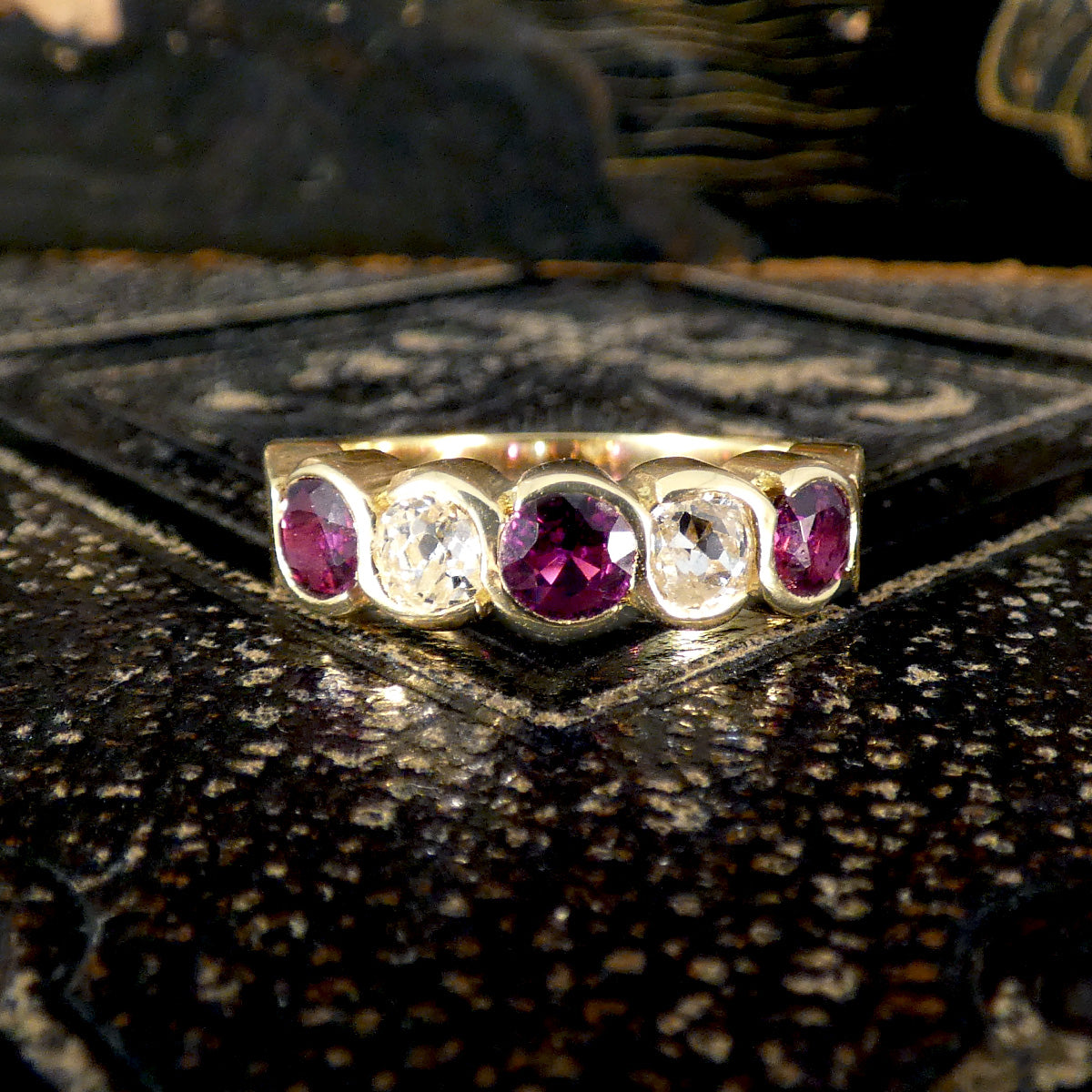 Vintage five-stone ring showcasing vibrant rubies and sparkling diamonds in a bold, chunky design, crafted in 18ct yellow gold with a waved bezel setting.