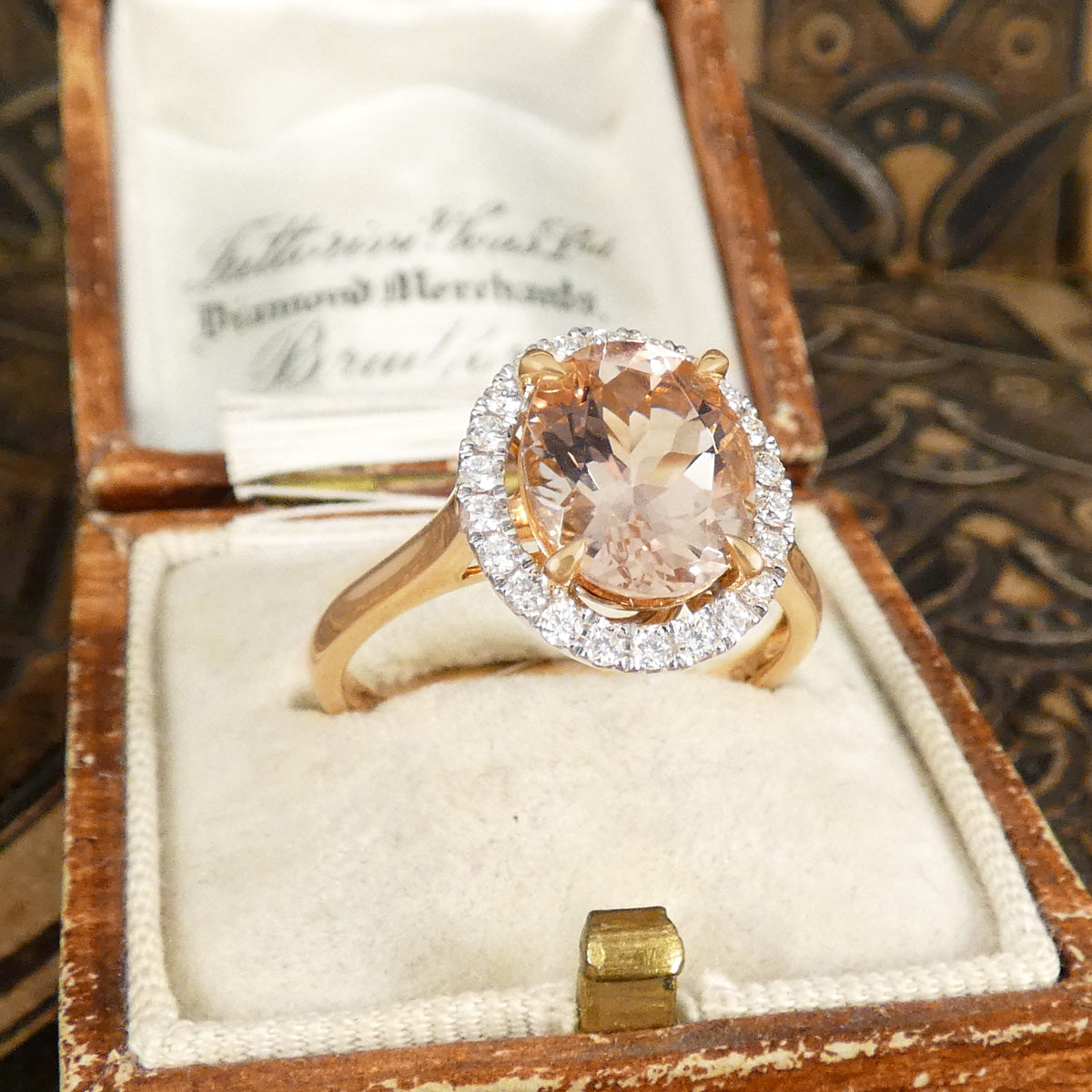 2.51ct Oval Cut Morganite and Diamond Halo cluster ring in 18ct White and Rose gold. The Morganite is showing a lovely peachy pink hue with a four spiked claw setting.