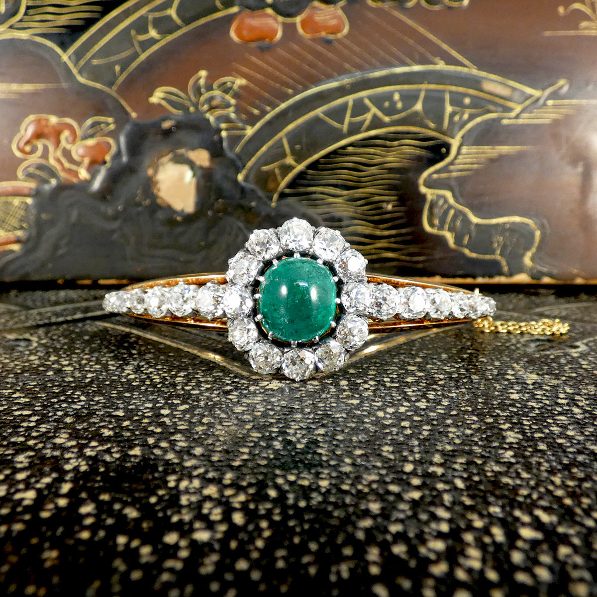 A striking late Victorian cabochon emerald and diamond bangle featuring approximately 8.50ct chunky old-cut diamonds surrounding the central 5.30ct emerald, showcasing timeless elegance and exceptional craftsmanship.