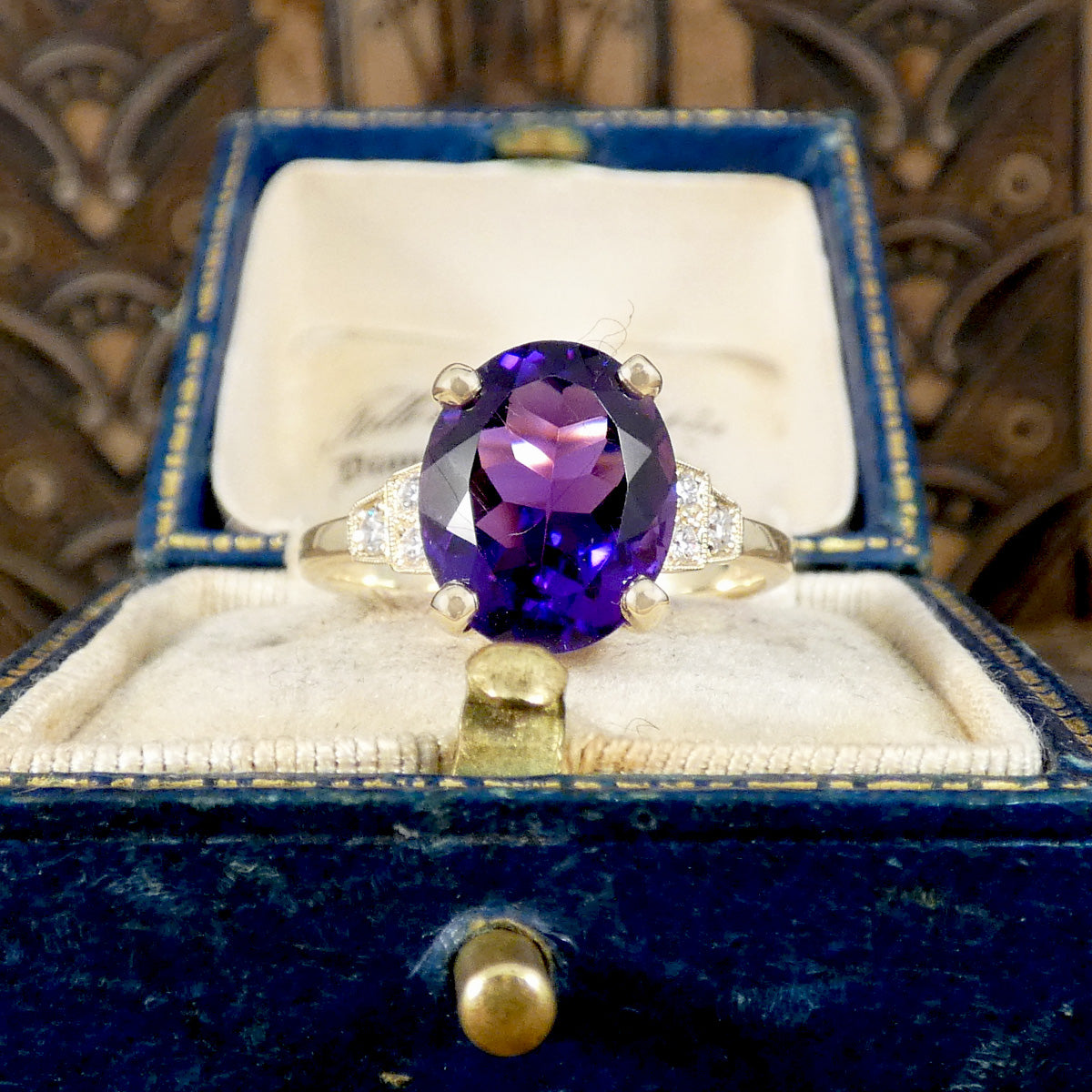 Bright and vibrant amethyst ring in a four claw setting with diamond set shoulders in 9ct yellow gold.