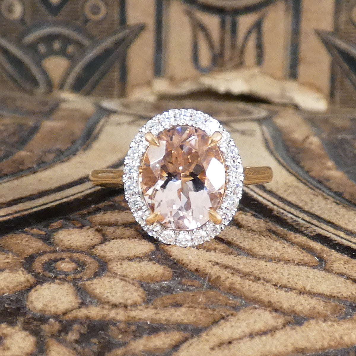 2.51ct Oval Cut Morganite and Diamond Halo cluster ring in 18ct White and Rose gold. The Morganite is showing a lovely peachy pink hue with a four spiked claw setting.