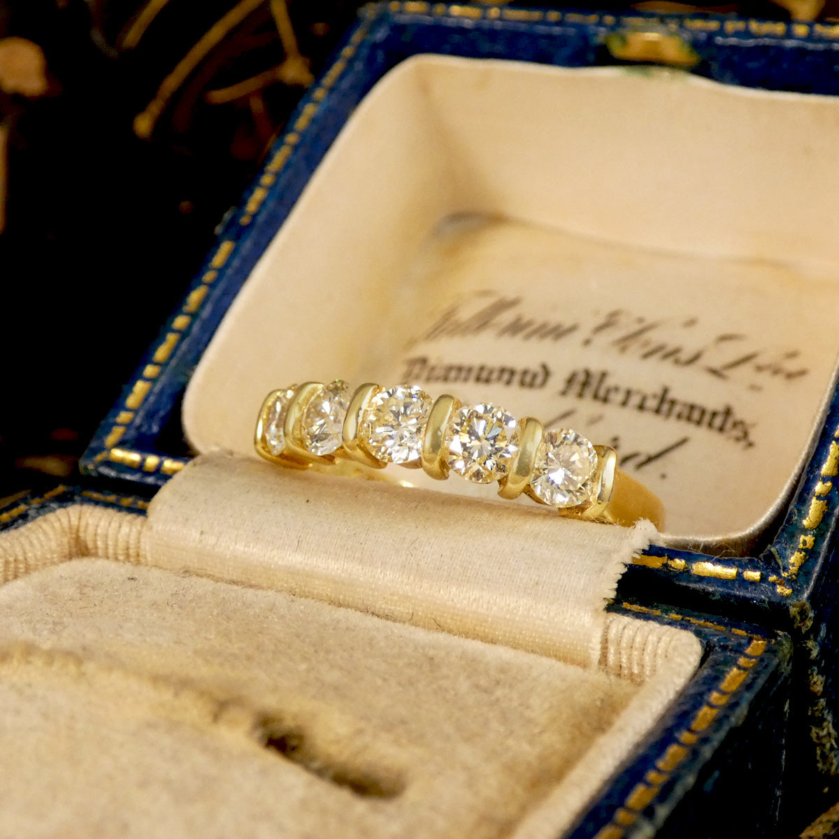 Diamond Five stone ring shown in an antique box with a warm and yellow gold appearance.