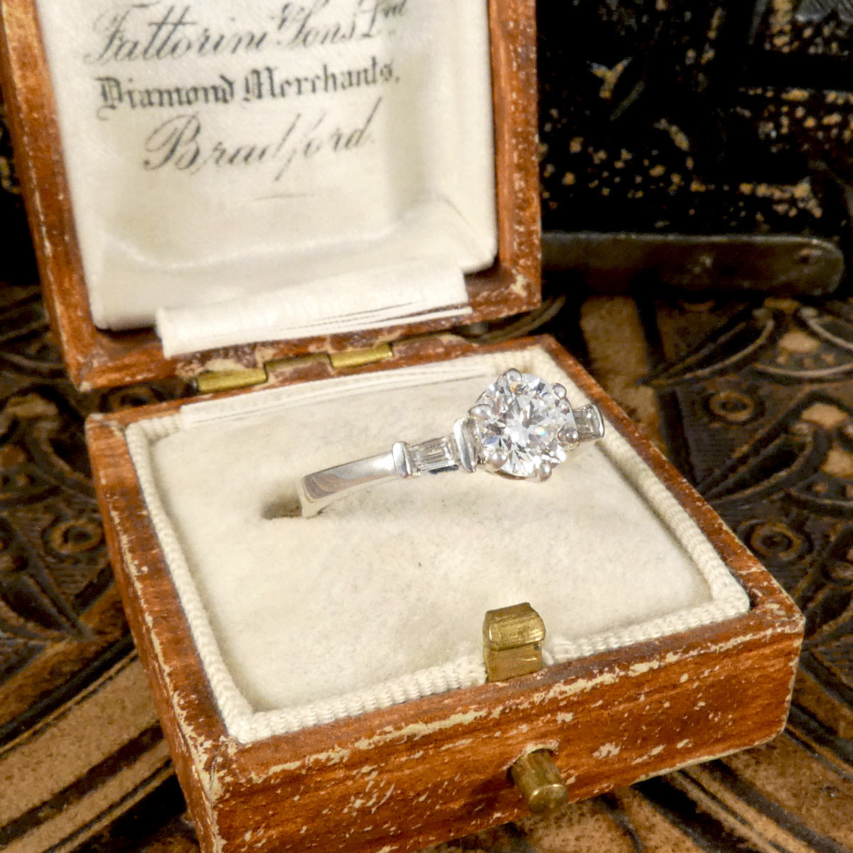 A classic brilliant cut diamond solitaire with baguette cut diamond shoulders in 18ct white gold. GIA certed diamond in a six claw setting, the perfect engagement ring. Side view in vintage ring box.