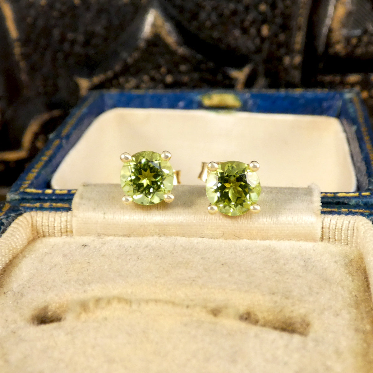 Close up of four-claw peridot stud earrings crafted in 9ct yellow gold, featuring vibrant round-cut green gemstones with a classic and elegant design.