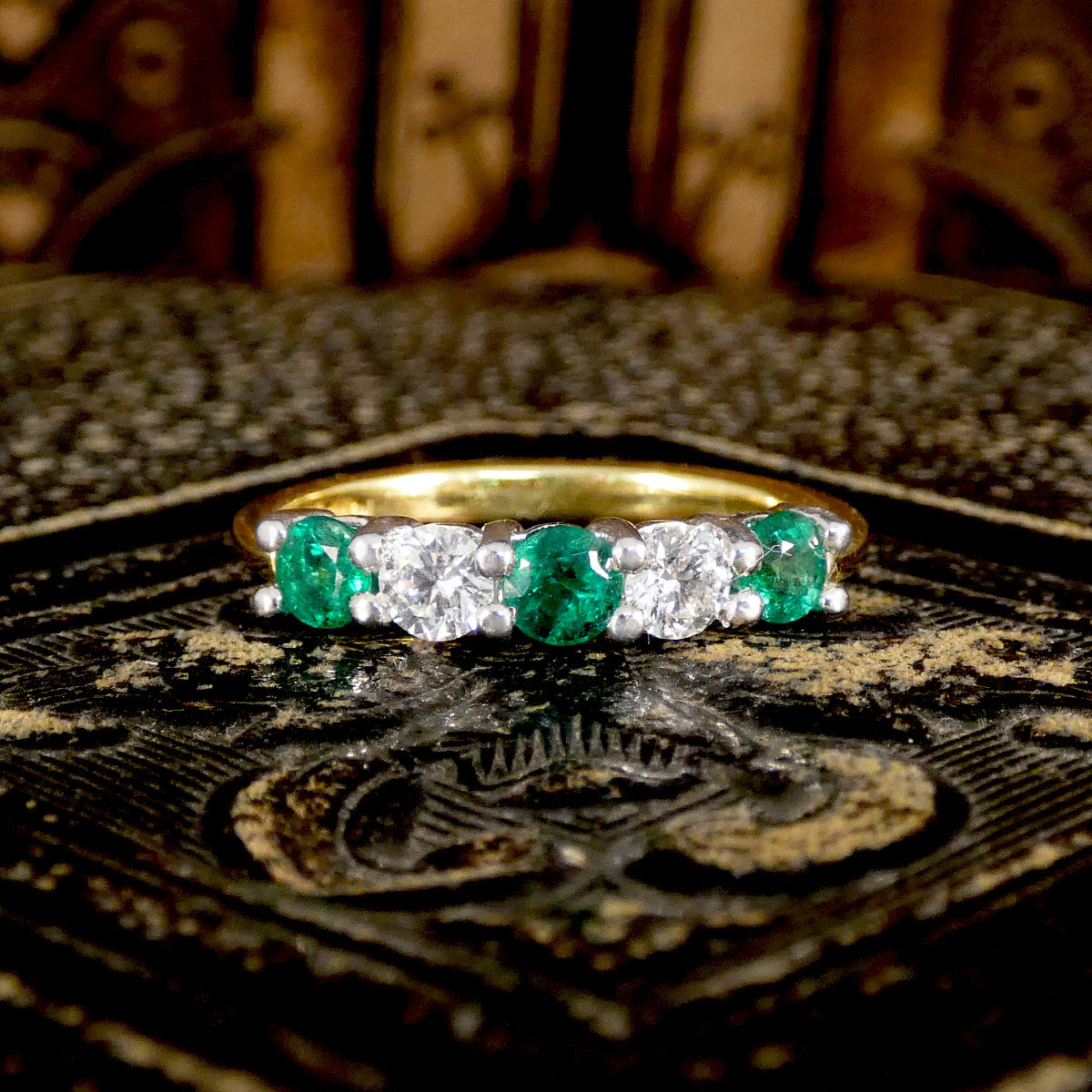 Featuring bright and vibrant emeralds sandwiching bright and clear diamonds in a five stone band ring.