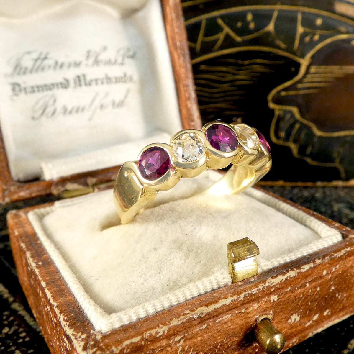 Vintage five-stone ring showcasing vibrant rubies and sparkling diamonds in a bold, chunky design, crafted in 18ct yellow gold with a waved bezel setting. Shown in vintage box.